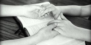 Holding hands over Bible